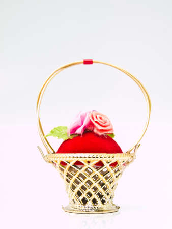 A miniature metalic wicker decorated by roses on a red velvet isolated on white backgroundの写真素材