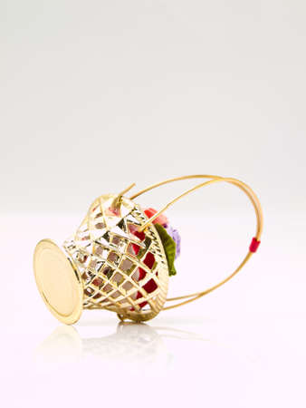 A miniature metalic wicker decorated by roses on a red velvet isolated on white backgroundの写真素材