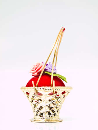 A miniature metalic wicker decorated by roses on a red velvet isolated on white backgroundの写真素材