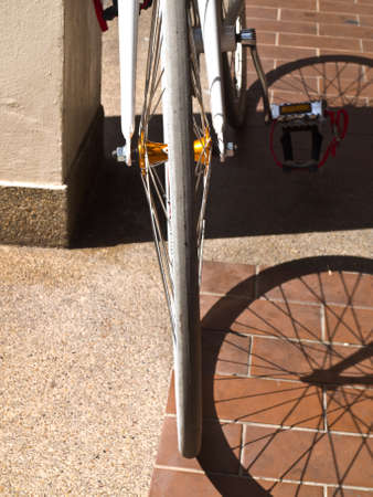 Part of bike wheel and its shadow on floor tileの写真素材