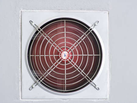 A red industrial ventilated fan on grey wall as backgroundの写真素材