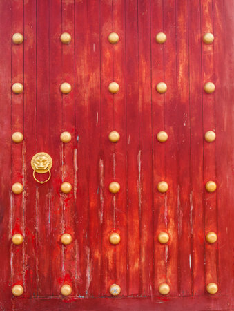 ancient red wooden gate with lion door knockerの写真素材