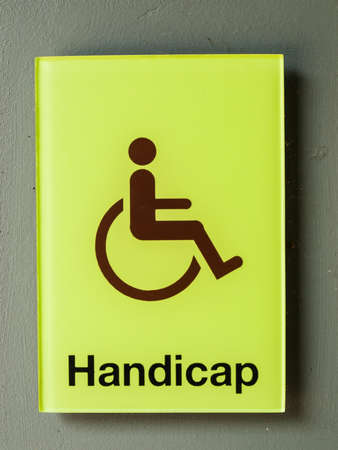 Green glass handicap sign on grey wallの写真素材