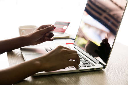 Asian female office worker typing on her laptop and holding credit card on left handの写真素材