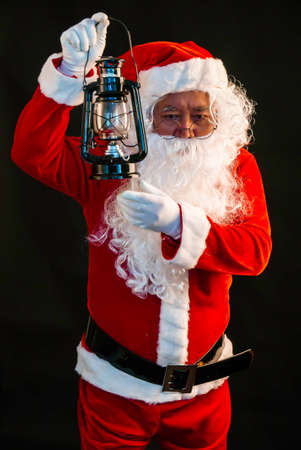 Santa Claus holding lantern for lighting studio shot on black background for family, giving, season, Christmas, holiday, new year, travel, Christian and gathering conceptの写真素材