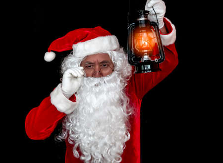 Santa Claus holding lantern for lighting studio shot on black background for family, giving, season, Christmas, holiday, new year, travel, Christian and gathering conceptの写真素材