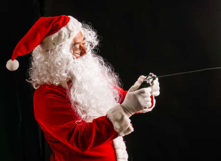 Santa Claus playing game studio shot on black background for family, giving, season, Christmas, holiday, new year, travel, Christian and gathering conceptの写真素材