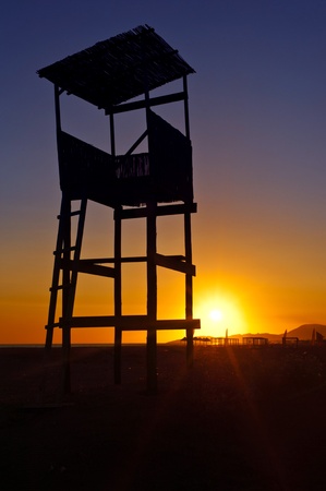 Sunset silhouette of the lifeguard observation tower at the beachの写真素材