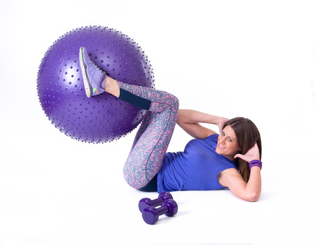 Sport woman exercising with a purple pilates ball and dumbbells  Isolated on a white background  Studio shotの写真素材