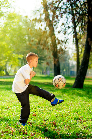 Young boy play football on the sunny meadow の写真素材