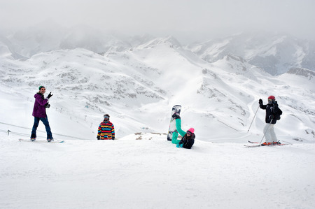 Happy snowboarders and skiers enjoy on top of mountain Happy four sportsmen with snowboard and skis standing on top of mountainの写真素材