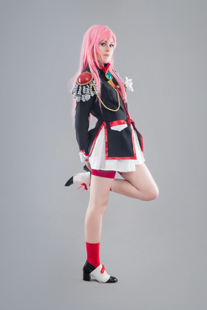 Japanese school uniform.  Girl dressed in Japanese school uniform with sword isolated on the gray backgroundの写真素材