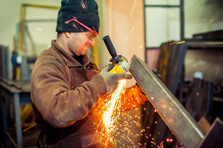 Electric grinder. A man working with electric grinder tool  on steel structure in factory, sparks...