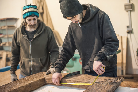 Professional carpenter at work measuring wooden planksの写真素材