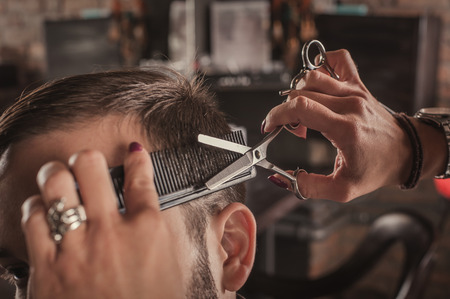 Skillful female hairdresser hairstyle hair of attractive man in hair salon. Close up.の写真素材