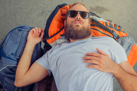 Closeup of handsome male backpacker tourist napping on a bench and baggage at the stationの写真素材
