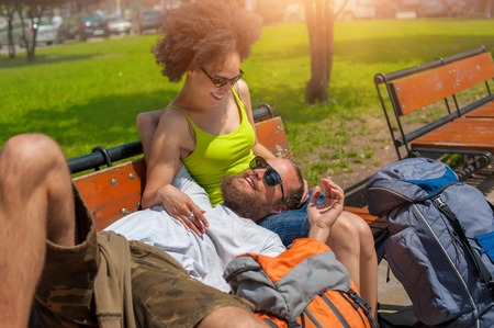 Lovely young couple resting together on a wooden bench in the parkの写真素材