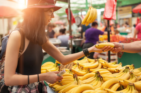 A young woman buying fruits and vegetables at a weekly market.の写真素材