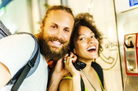 Young couple using payphones in streetの写真素材
