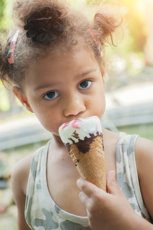 Cute little girl eating ice cream cone on the street