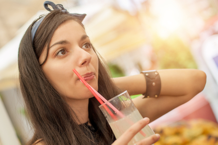 Gorgeous young brunette drinking lemonade, summer heat refreshmentの写真素材