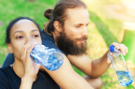 Man and woman drinking water from bottle after fitness sport exerciseの写真素材