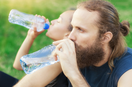 Man and woman drinking water from bottle after fitness sport exerciseの写真素材