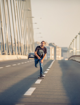 Professional skateboarder riding a skate over a city road bridge, through urban traffic. Free ride skateboardsの写真素材
