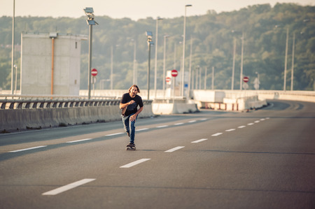 Professional skateboarder riding a skate over a city road bridge, through urban traffic. Free ride skateboardsの写真素材