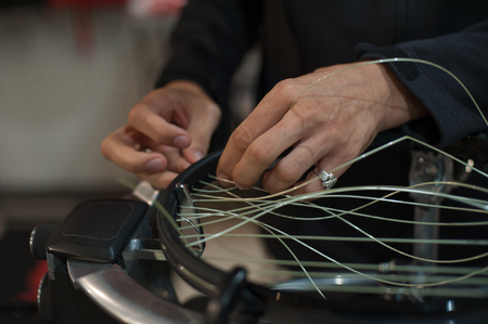 Stringing Machine. Close up of tennis stringer hands doing racket stringing in his workshopの写真素材