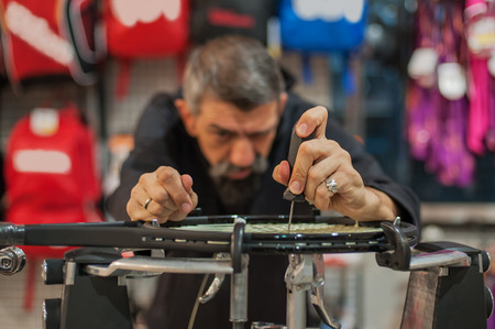 Stringing Machine. Detail of tennis stringer hands while holding awl and doing racket stringingの写真素材