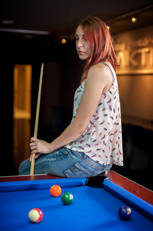 Young woman playing billiard in a pool hall
