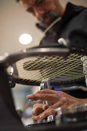 Stringing Machine. Close up of tennis stringer hands doing racket stringing in his workshopの写真素材