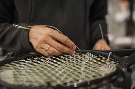 Stringing Machine. Close up of tennis stringer hands doing racket stringing in his workshopの写真素材