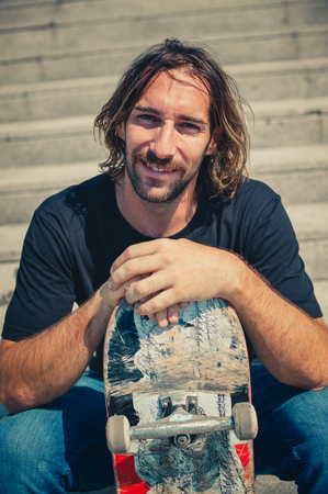 Skater is resting with skate board on the stairs. Free ride street skateboardingの写真素材