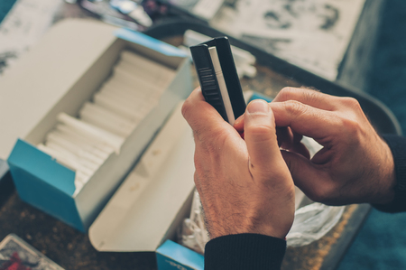 Smoker man roll domestic tobacco cigarettes using rolling machine. Close upの写真素材