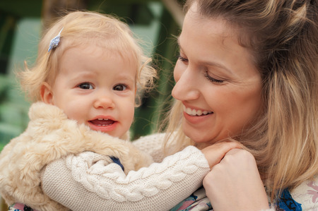 Portrait of a mother carrying her little baby in a baby carrier scurf in the parkの写真素材