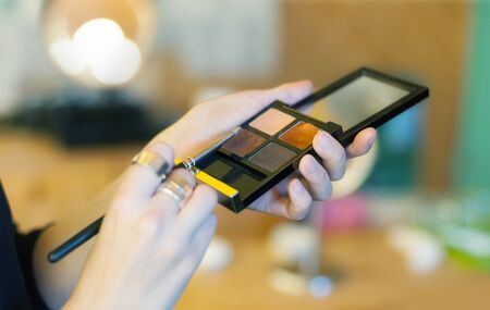 Makeup artist stylist applying eyeshadow on eyelid of womanの写真素材