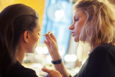 Makeup artist attaches with fingers and forceps false eyelashes on the upper eyelid of modelの写真素材