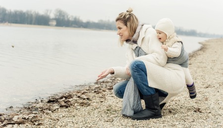 Portrait of a mother carrying her little baby in a baby carrier scurf in the parkの写真素材