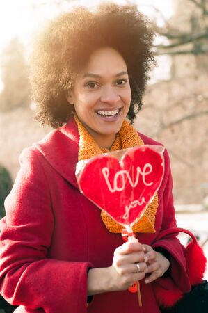 Happy young woman in the red coat holding a red heart. Valentines Dayの写真素材