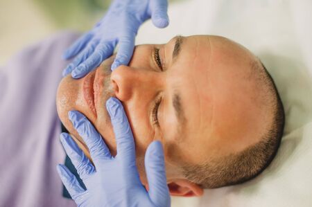 Relaxed man having a face massage and a peeling treatment at a beauty salonの写真素材