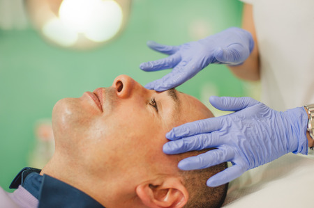 Relaxed man having a face massage and a peeling treatment at a beauty salonの写真素材