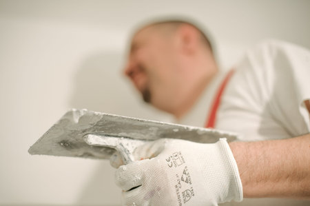 Construction worker plastering a wall with a spatula in a home renovation concept