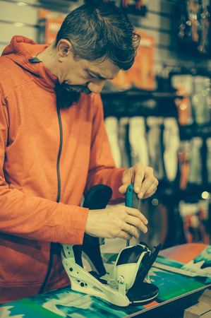 Snowboard repair shop worker adjust the bindings and equipment. Winter workshop serviceの写真素材