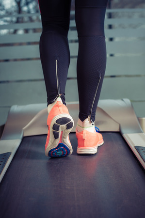 Fitness girl with muscular legs running on treadmill in the gymの写真素材