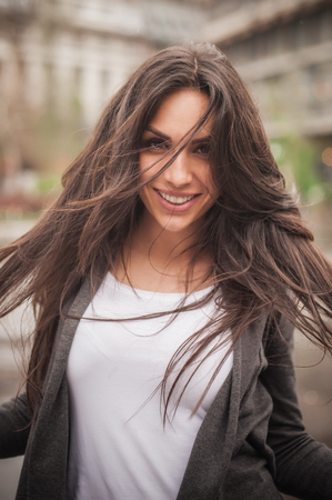 Happy cheerful smiling woman enjoys on the city streets during a beautiful dayの写真素材