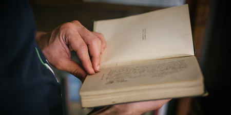 Curious man choosing book in his library at home. Close upの写真素材