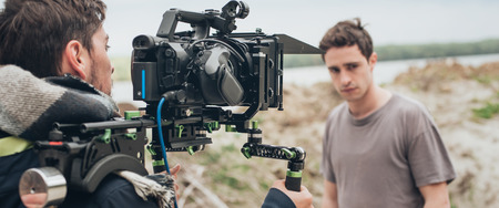 Behind the scene. Actor in front of the camera on the film set outdoor location. Group movie sceneの写真素材