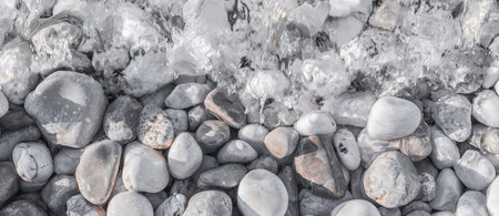 Sea pebbles on the beach under a layer of transparent water. Close-up shot